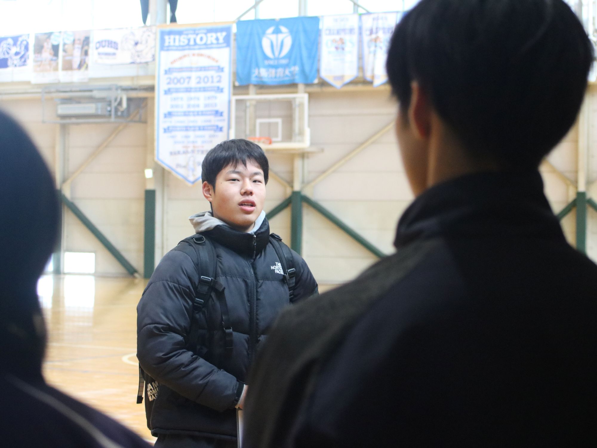 施設紹介をする竹下翔太さん(体育学部3年・バスケットボール部男子学生コーチ)、コートが2面とれるバスケットボール専用体育館で