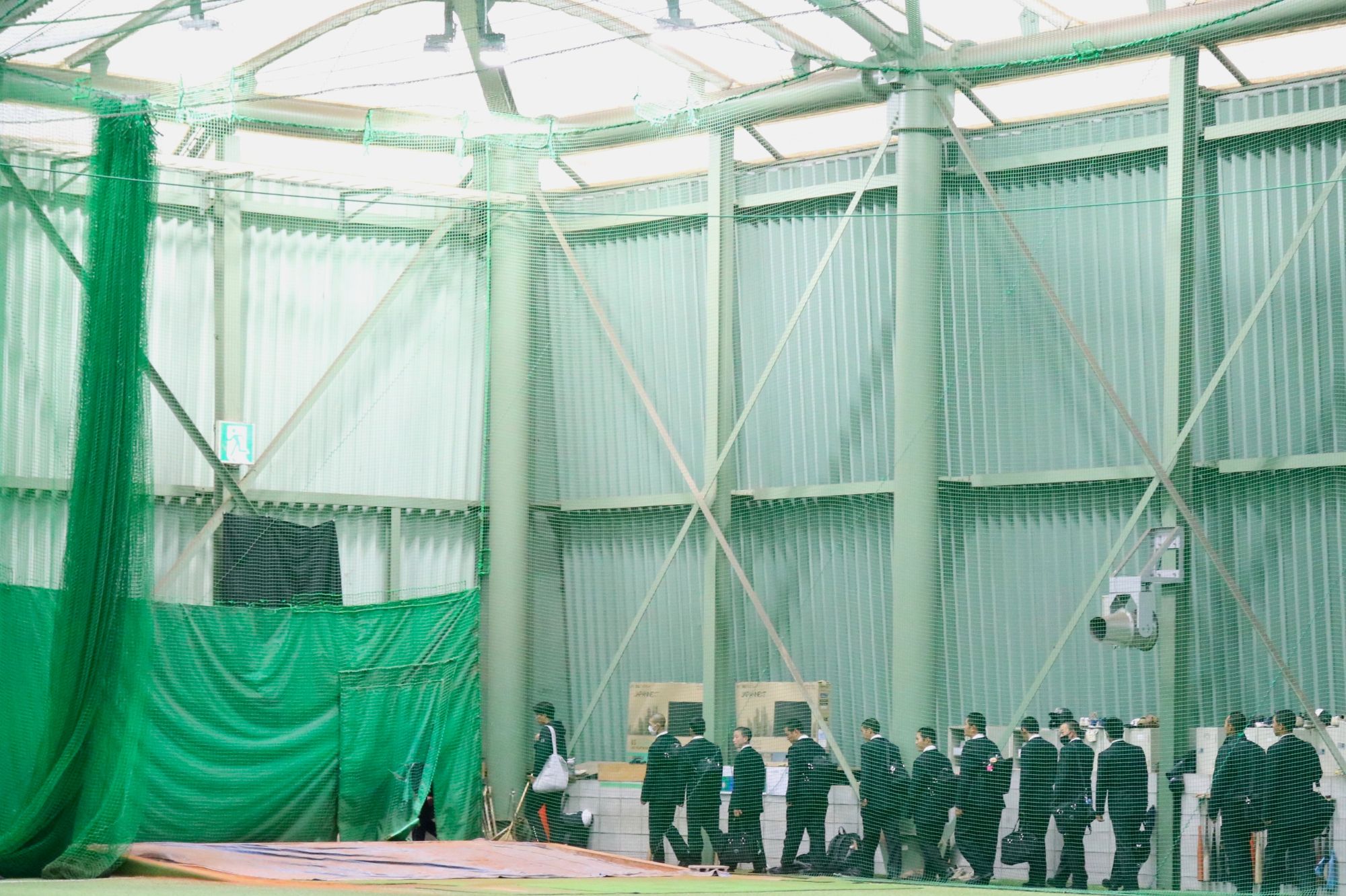 大学球界屈指の広さを誇る屋内野球練習場を見学する生徒たち