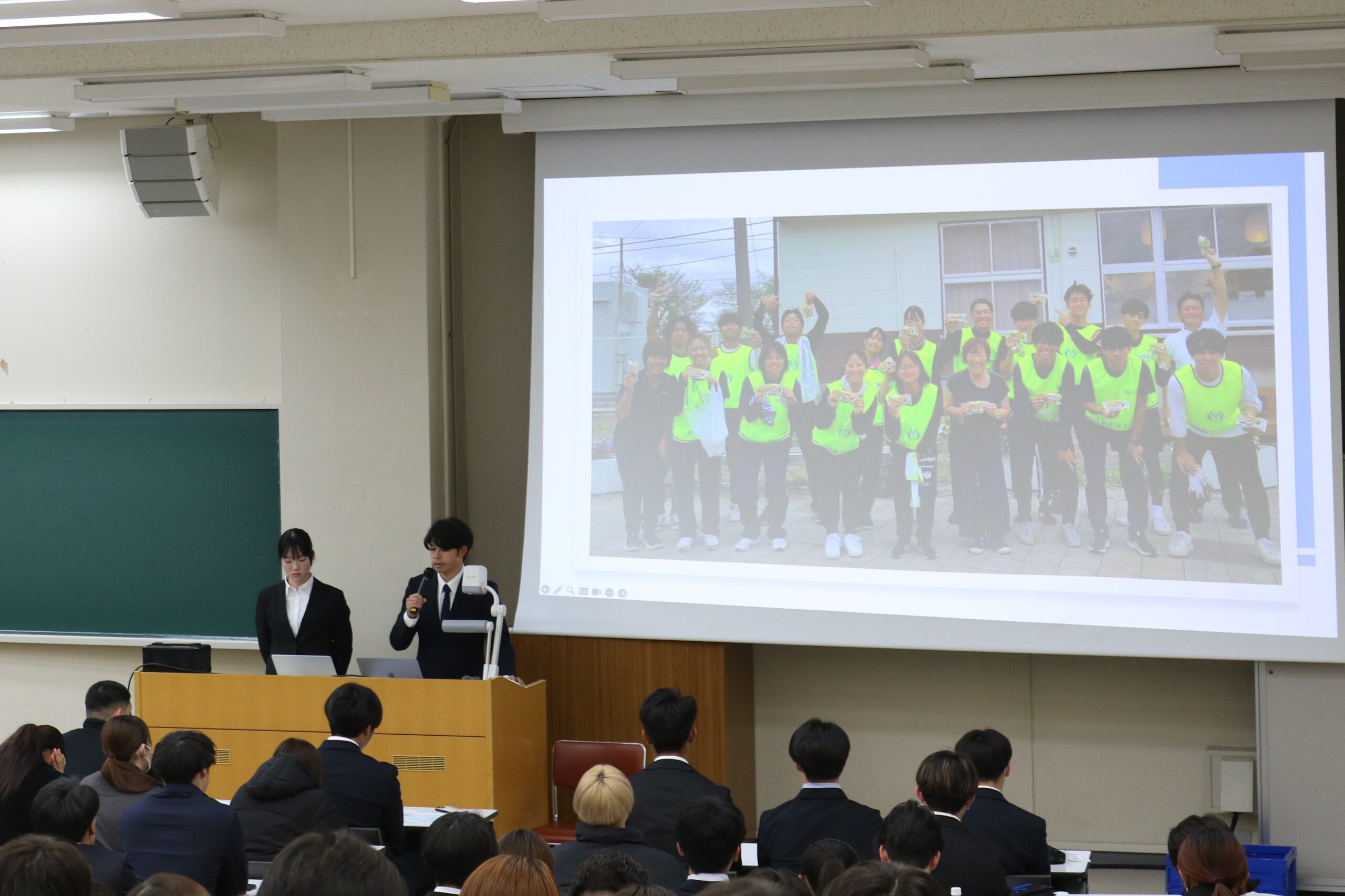 D号館での報告会の様子、左から市川ほのかさん(教育学部2年)、中尾海世(かいせい)さん(体育学部4年)