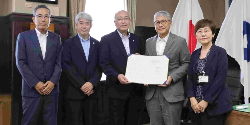 協定書を手にする神﨑浩学長（右から３人目）、宮﨑泉知事（２人目）。大阪体育大学・三島隆章スポーツ科学部長、梅林薫スポーツ局長（４、５人目）、和歌山県・北村香企画部長