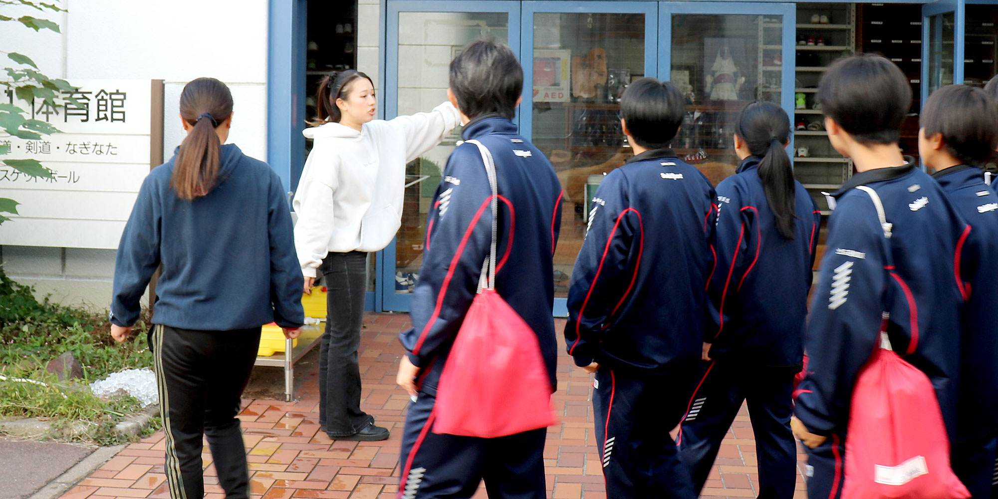 福知山成美高校OGで体育学部4年・阪上天海さん（左から2番目）が専用体育館の説明をする