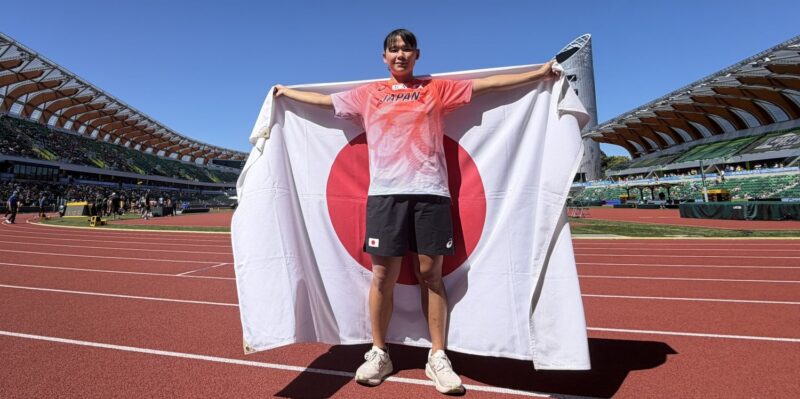 オレゴンの会場で日の丸を掲げる大阪体育大学・鈴木彩夏（スポーツ科学部１年、大阪体育大学浪商高校）＝中西啄真・大阪体育大学陸上競技部投てきブロック監督撮影 【大阪体育大学】