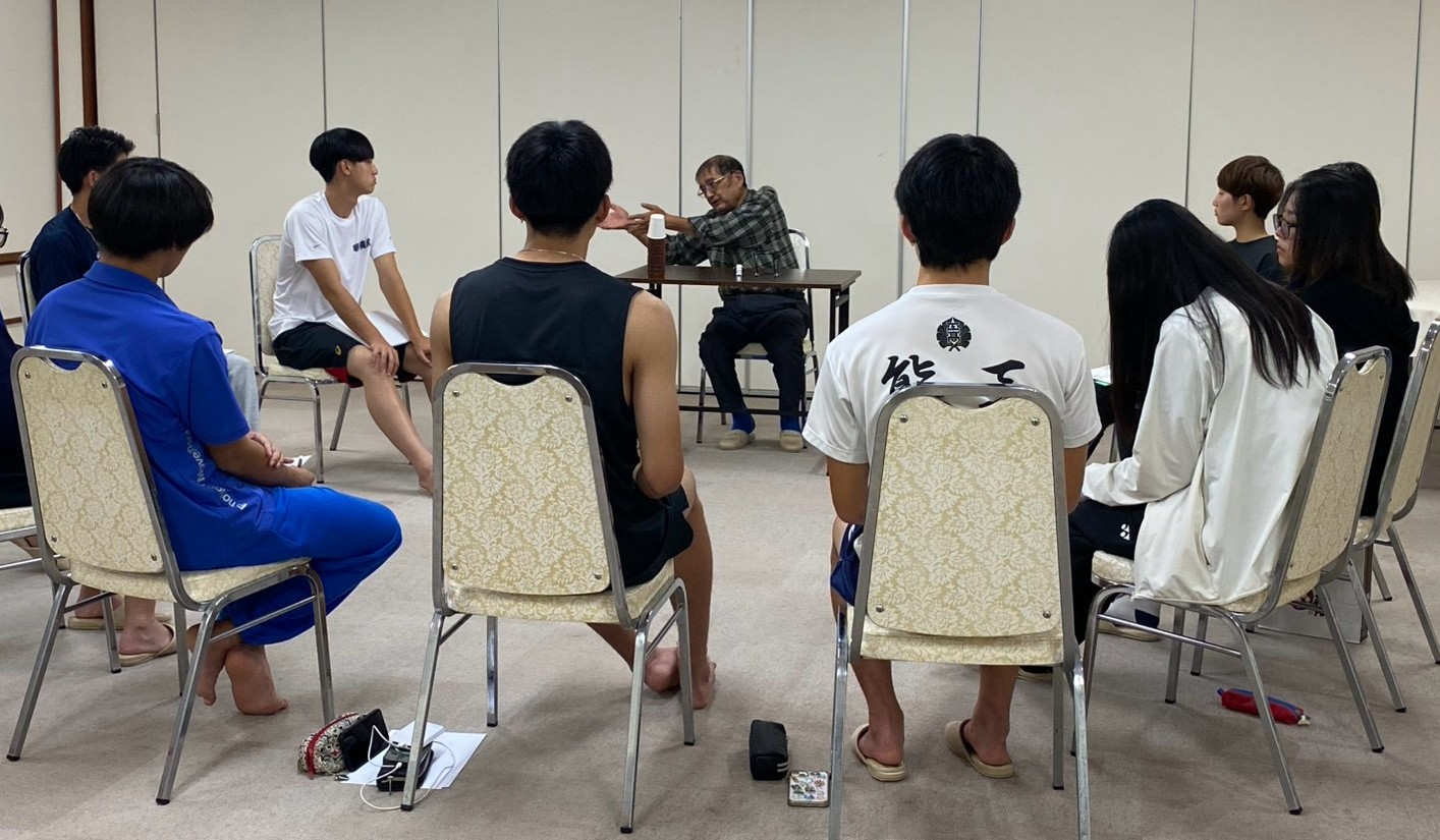 夜は宿舎でNPO法人「つながっぺ南相馬」元代表の今野由喜さんの体験談を聞いた。今野さんは津波で車の中に閉じ込められ、水が頭の高さにまで来た時、友人に助けられた。以後、南相馬市小高区の復興に尽力し、サンライズキャンプでは長年、地元の受け入れ体制を整えてもらった 【大阪体育大学】