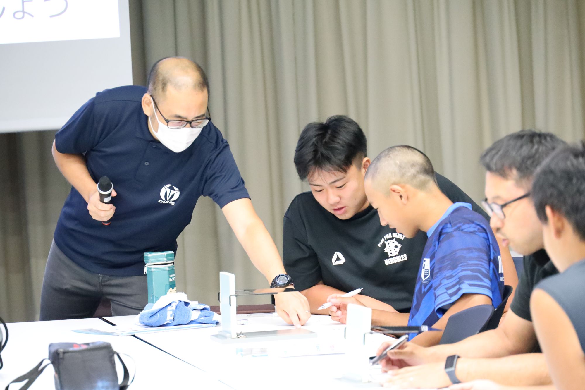 高校生にアドバイスする手塚教授（右）と高校生を見守る本学ラグビー部学生（中央）
