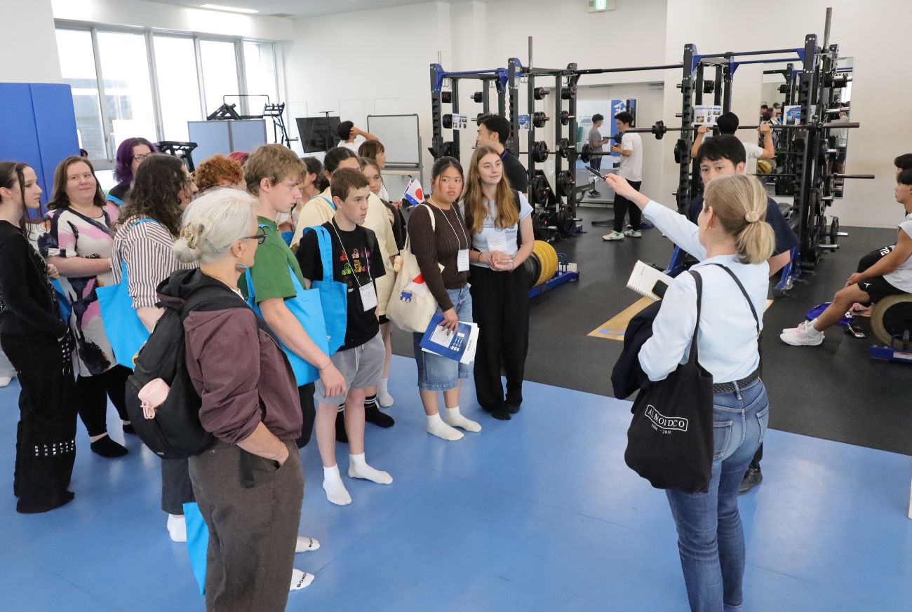 S＆Cルームを見学する参加者。トレーニング中の学生と記念写真を撮るなど、すぐに打ち解けた 【大阪体育大学】