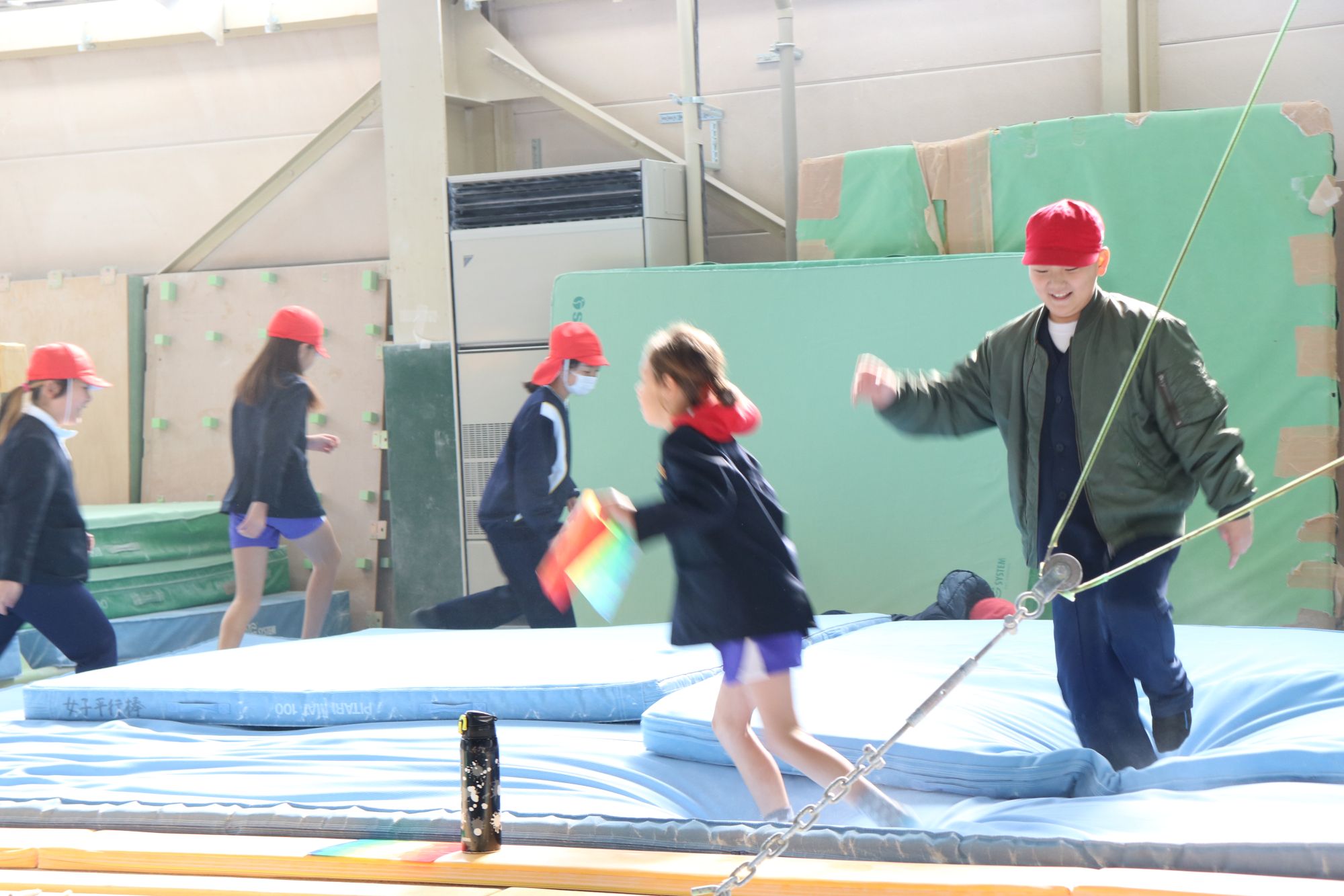 ふかふかのマットの上を飛んだりはねたりする児童