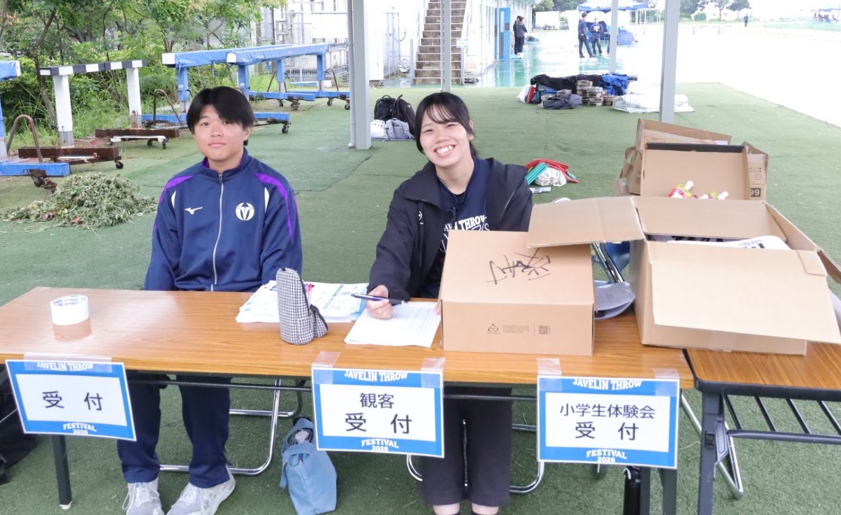 受け付けは学生マネジメントチーム(右)と陸上競技部(左)がコンビで担当。来場者にマフラータオルをプレゼント 【大阪体育大学】